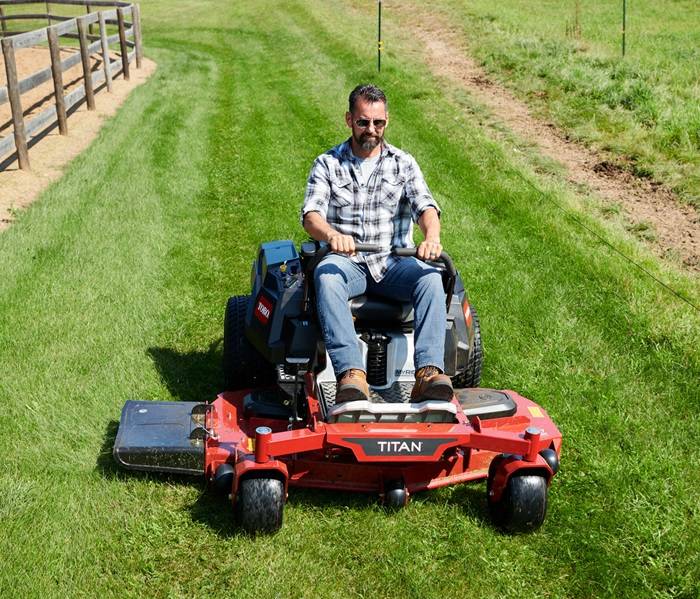 Routine Yard Maintenance with Gas-Powered Mower Person mowing green grass with a heavy-duty riding mower.